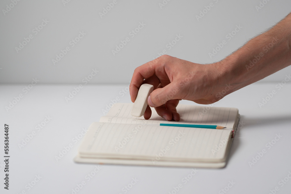 student holding the rubber and erasing errors in notebook student holding the rubber and erasing errors in notebook