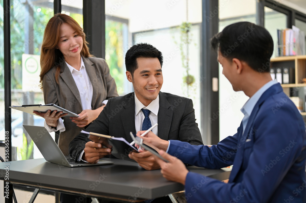 Smart Asian businessman talking and working with his financial employees in the office. Smart Asian businessman talking and working with his financial employees in the office.