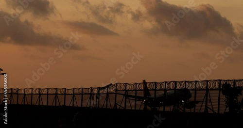 Silhouette of the plane lands at airport against backdrop of evening sunset sky. Plane landing on runway. Arrival at the airport. Travel, tourism to warm countries. Holidays in the southern countries