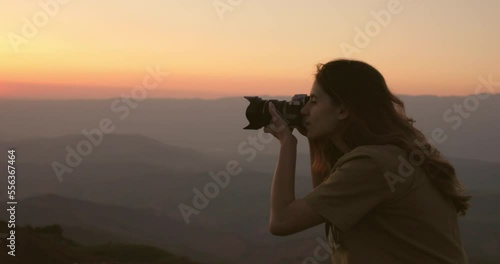Wallpaper Mural A woman photographer against the background of a foggy hilly valley takes beautiful pictures of an orange-pink sunset. A woman captures the landscape of the setting sun in the mountains with a camera. Torontodigital.ca