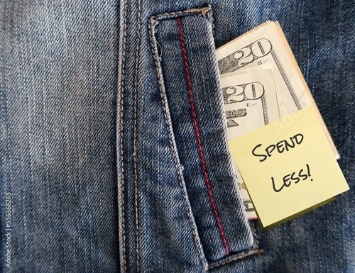 Dollars banknote cash in copy space Jeans pocket with note SPEND LESS, concept of set budget spending , set goal to be frugal and boost saving