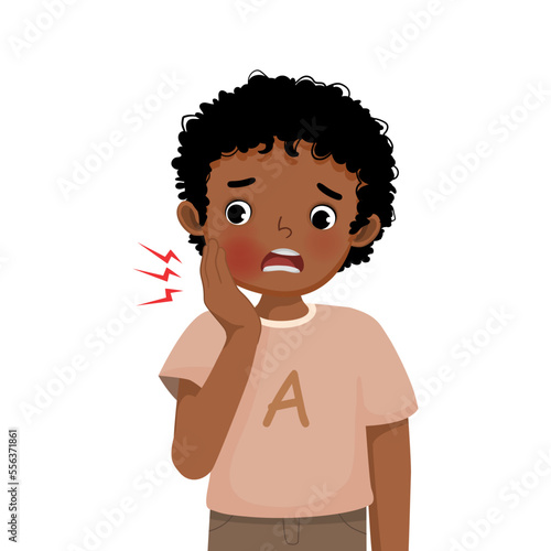 Cute little African boy suffering from toothache touching his cheek feeling painful
