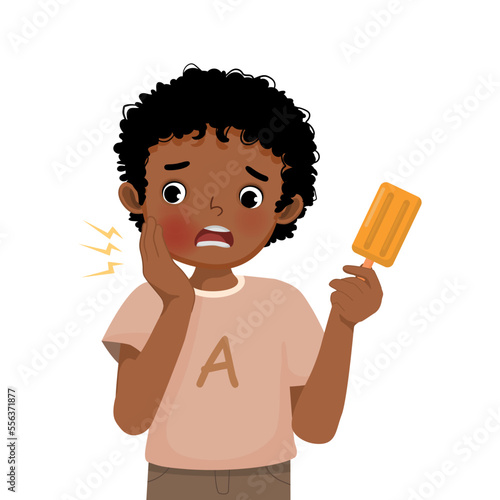 Cute little African boy with sensitive teeth having toothache while eating cold ice cream touching his cheek feel painful