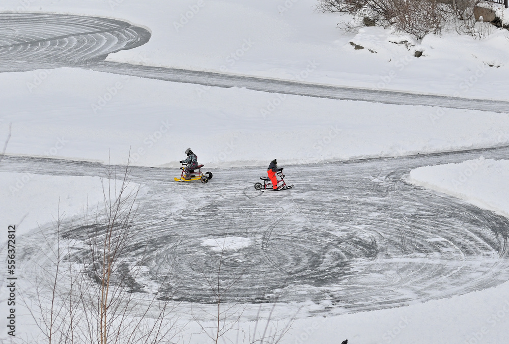 Boys ride electric scooters on the ice of the lake on a winter day