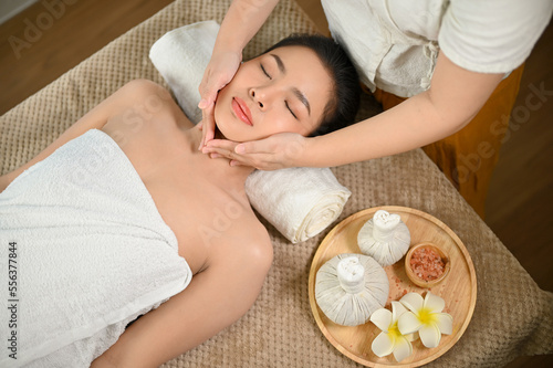 Calm and relaxed young Asian woman having facial massage or facial treatment at beauty spa salon