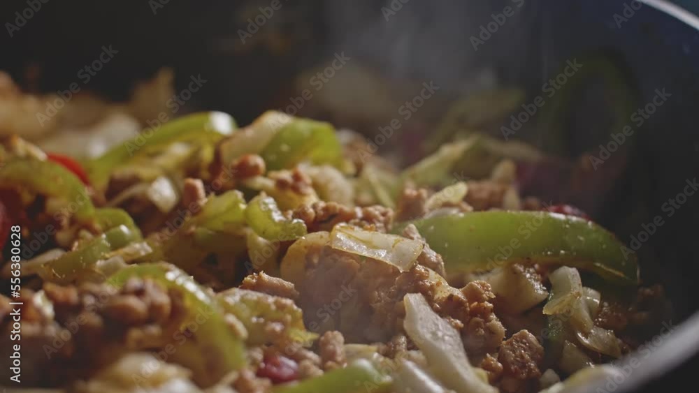 Pouring sauce in homemade mexican food and mixing it all with a wooden spoon, close up view. Pouring sauce in homemade mexican food and mixing it all with a wooden spoon, close up view.