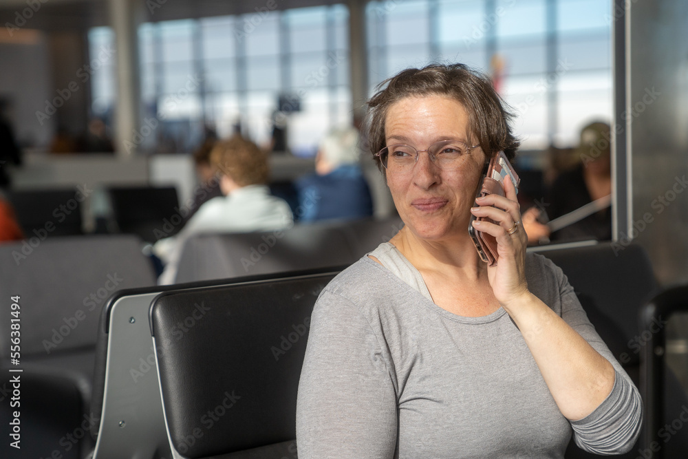 Woman at an airport waiting for flight working on her phone Woman at an airport waiting for flight working on her phone