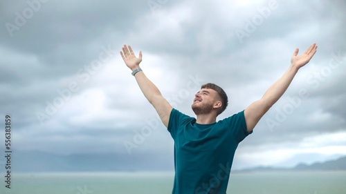 happy handsome free guy, young calm relaxed carefree man traveler with open raised hands enjoy sea, ocean view, person feeling good, breath deep deeply fresh air. Freedom, travel, happiness concept