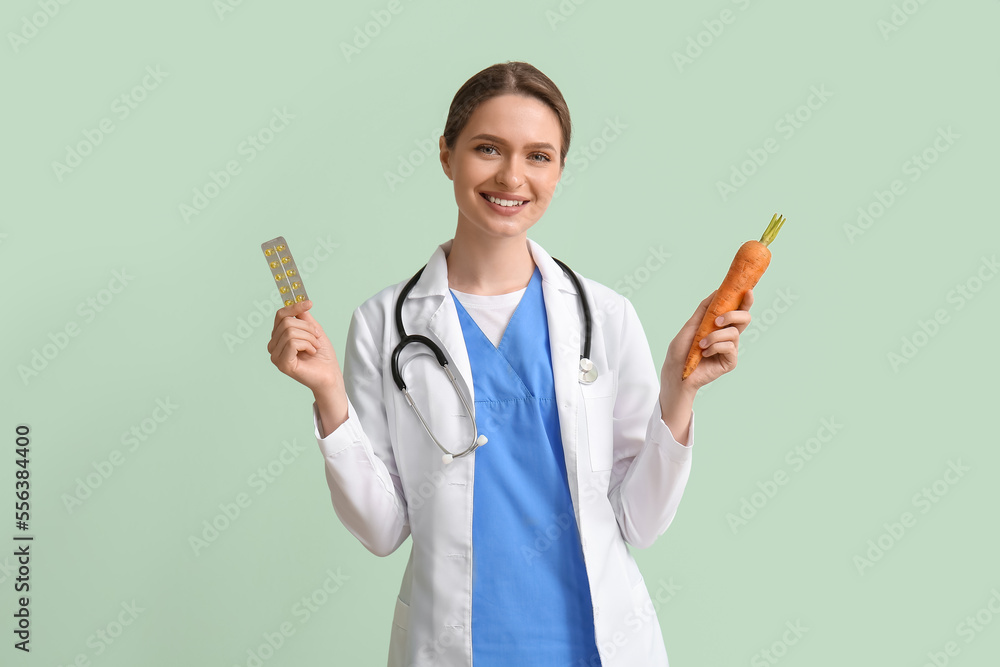 Female doctor with vitamins and carrot on green background Female doctor with vitamins and carrot on green background