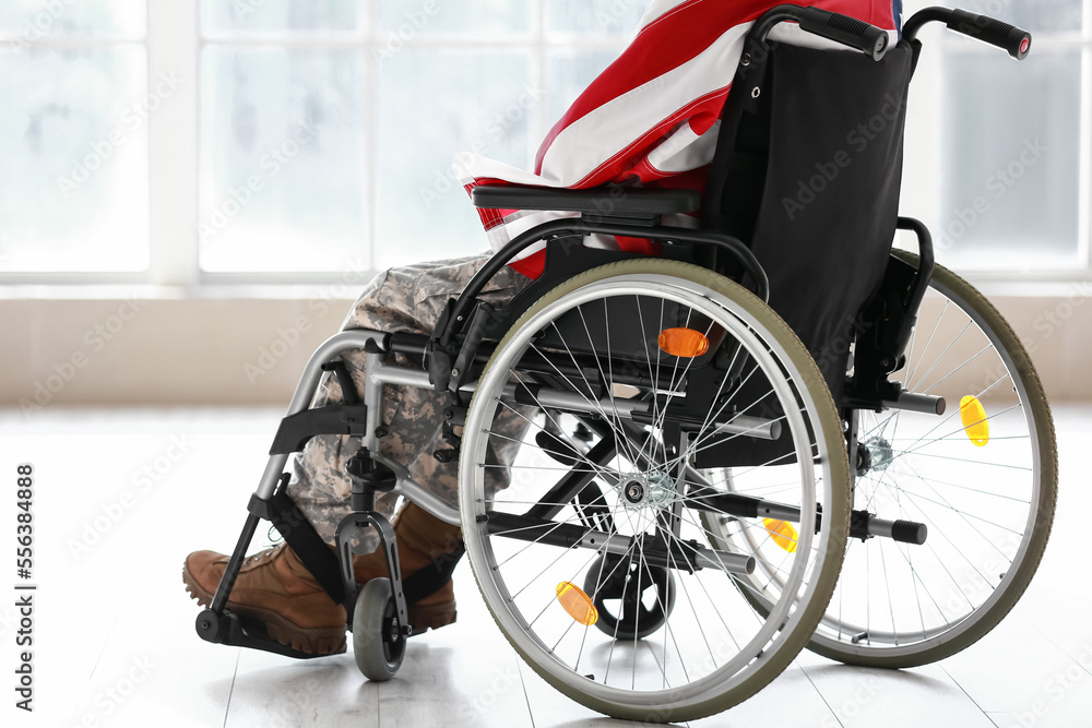 Fototapeta premium Young soldier in wheelchair with USA flag at home