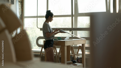 carpenter girl makes an oar, examines the workpiece