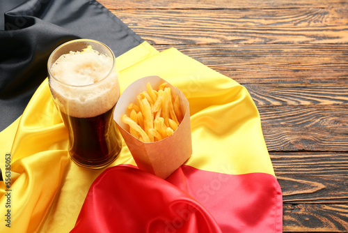 Belgium flag, glass of beer and paper box with french fries on wooden background