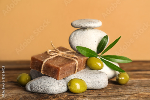 Soap bar with olives and stones on table near beige wall