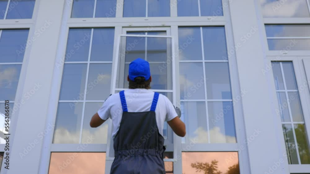 Thumbs up shows the working one after successfully installing a mosquito net on a large window of the house. Man in a work jumpsuit puts a protective net on the window Thumbs up shows the working one after successfully installing a mosquito net on a large window of the house. Man in a work jumpsuit puts a protective net on the window