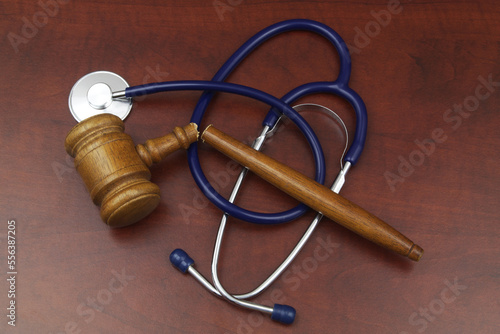Broken wooden judge gavel and stethoscope on table. Malpractice and medicine out of law concept.