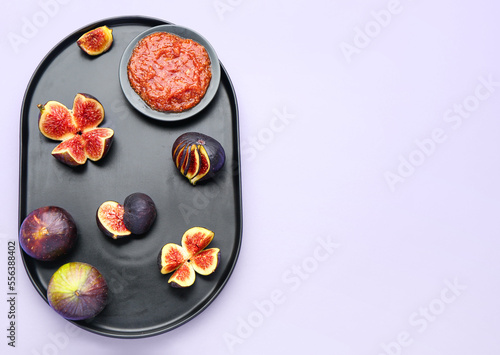 Plate with sweet figs and puree on lilac background