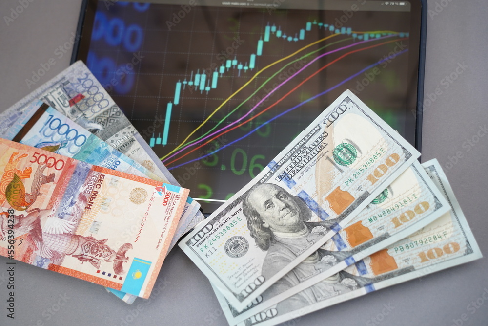 Almaty, Kazakhstan - 10.04.2022 : Stock charts on the tablet and tenge and dollar banknotes on the table. Almaty, Kazakhstan - 10.04.2022 : Stock charts on the tablet and tenge and dollar banknotes on the table.