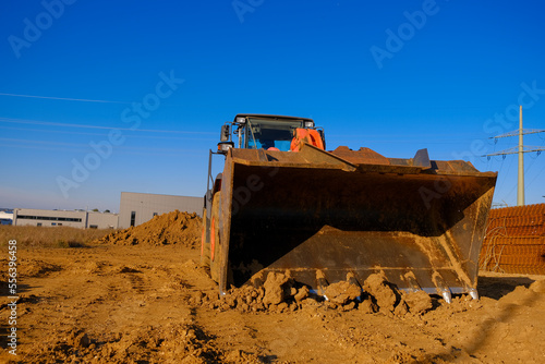  tractor with bucket in sand and clay.Excavator at construction site on houses and blue sky background.Construction of real estate and industrial premises concept.Construction equipment.