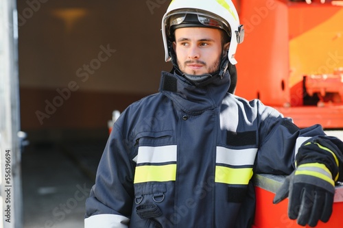 Fireman (firefighter) in action standing near a firetruck. Emergency safety. Protection, rescue from danger.