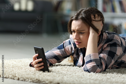 Sad teen checking phone on the floor at home Fototapet