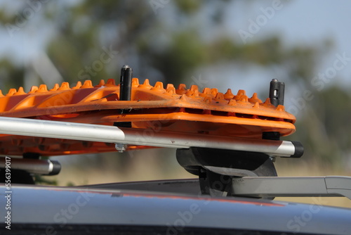 Orange recovery boards, tracks, ladders mounted on the roof rack. photo
