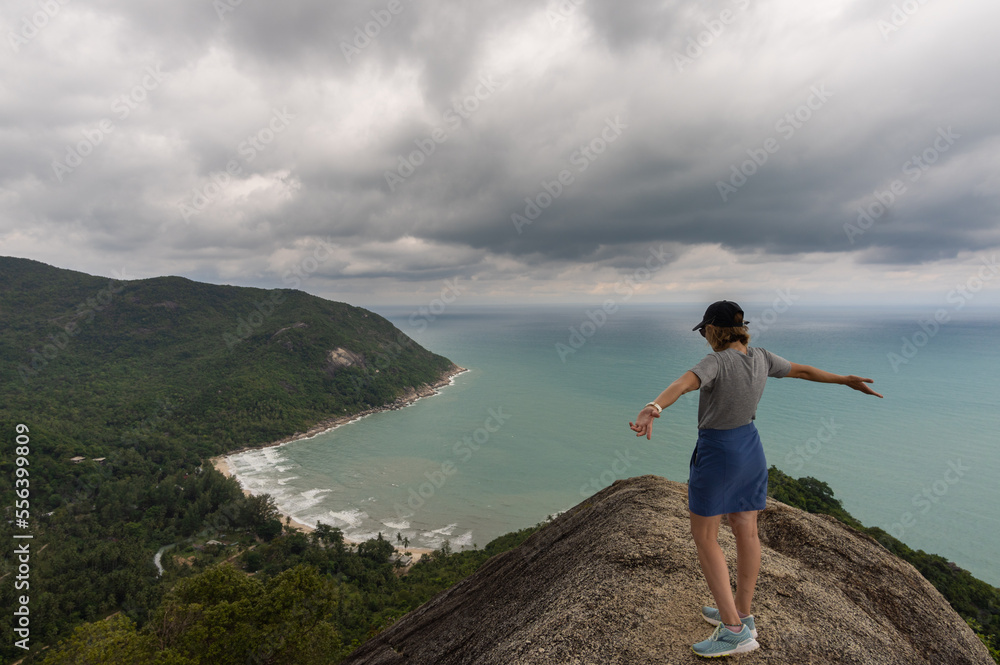 woman raising her arms on the bottle beach viewpoint , with clouds and beautiful tropical beach,koh phangan, Ko Pha-ngan, Surat Thani,thailand