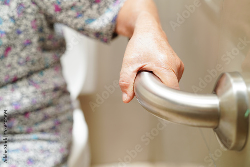 Asian elderly old woman patient use toilet support rail in bathroom, handrail safety grab bar, security in nursing hospital.