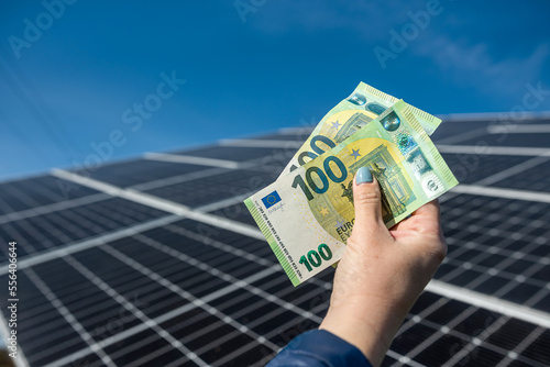 Human hands with euro fan in front of solar panels.