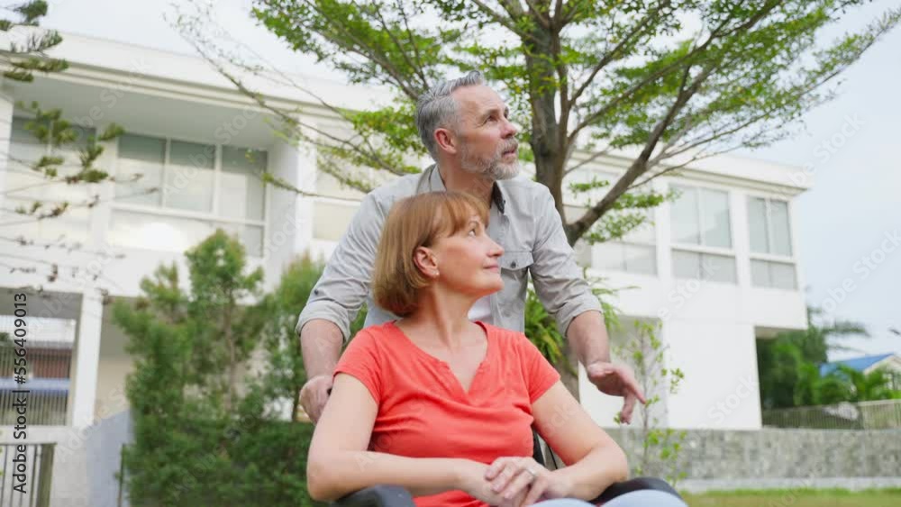 Caucasian senior man support his wife on wheelchair outdoors in garden. Caucasian senior man support his wife on wheelchair outdoors in garden.