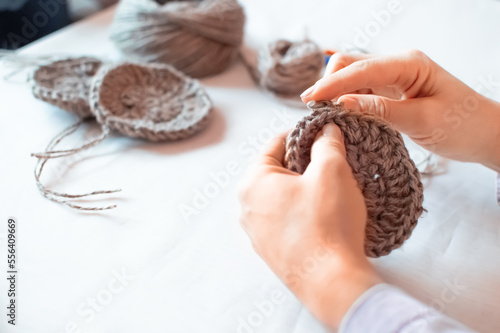 Close-up hands of a mature woman doing crocheting, making a hand-made jute.