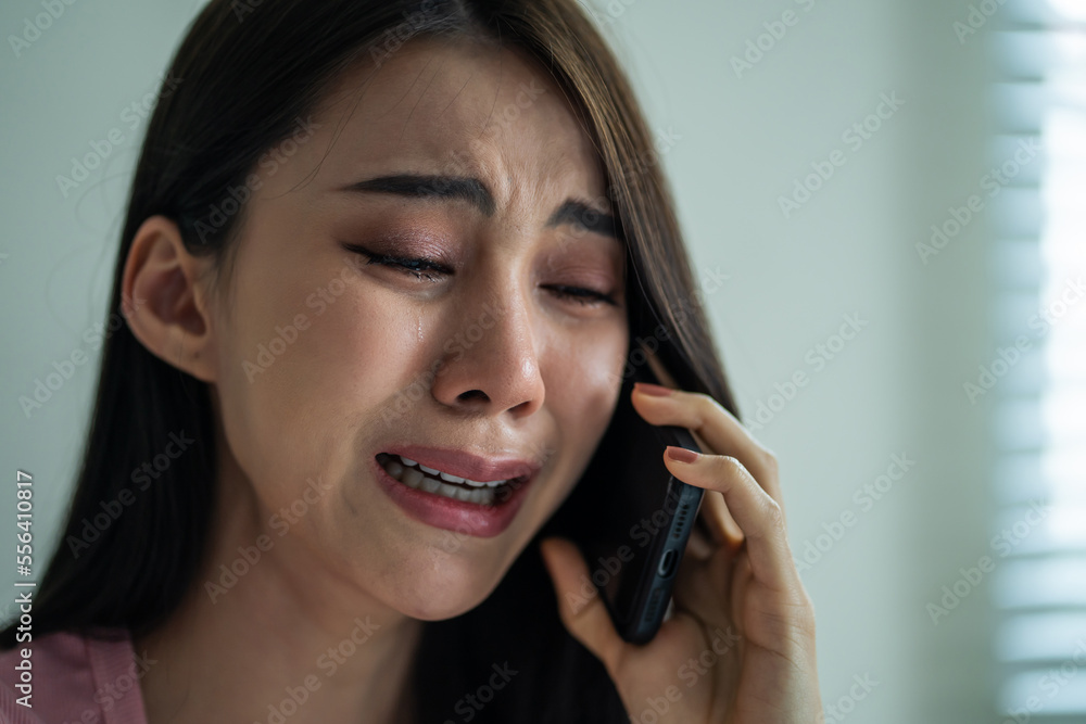 Asian upset depressed woman sitting on bed and talking on mobile phone. Asian upset depressed woman sitting on bed and talking on mobile phone.