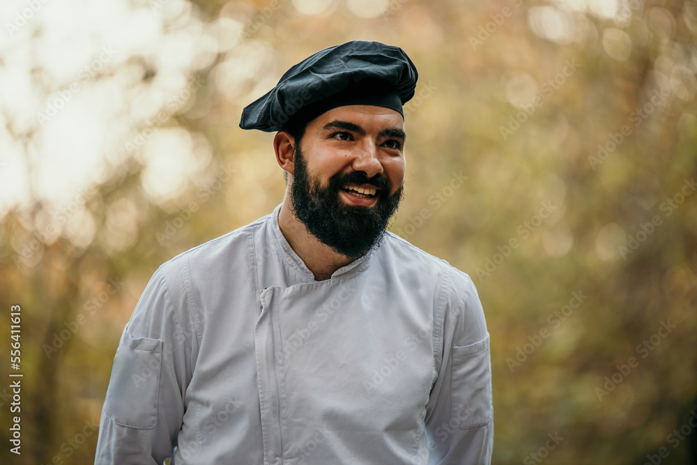 Smiling bearded handsome chef serving a food and setting up table for a garden wedding.