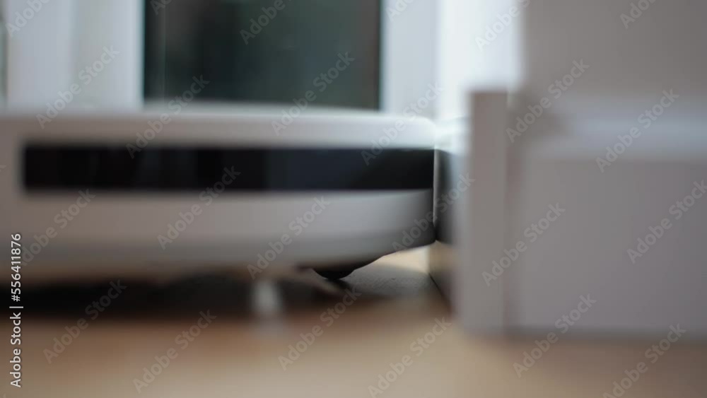 Closeup side view of wireless robot vacuum cleaner vacuuming floor in