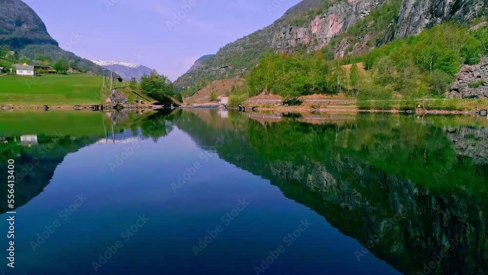 Aerial drone backward moving shot of village with traditional houses, located along the shore of a picturesque lake surrounded by mountain range at daytime. Aerial drone backward moving shot of village with traditional houses, located along the shore of a picturesque lake surrounded by mountain range at daytime.