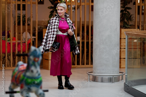 Beautiful adult woman walks shopping. Fashionable model wears trendy clothes tweed jacket, long dress, leather shoes