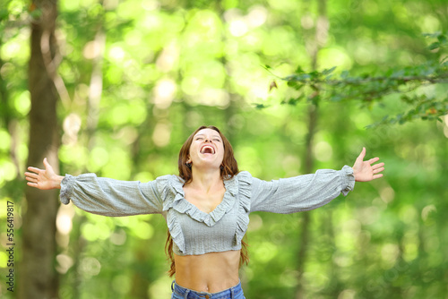 Excited woman celebrating in nature outstretching arms photo