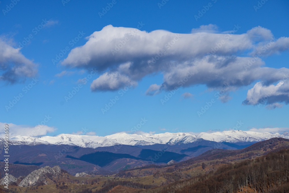 Mountains, snow, clouds in the blue sky. Snow-covered mountains, valleys and hills. 