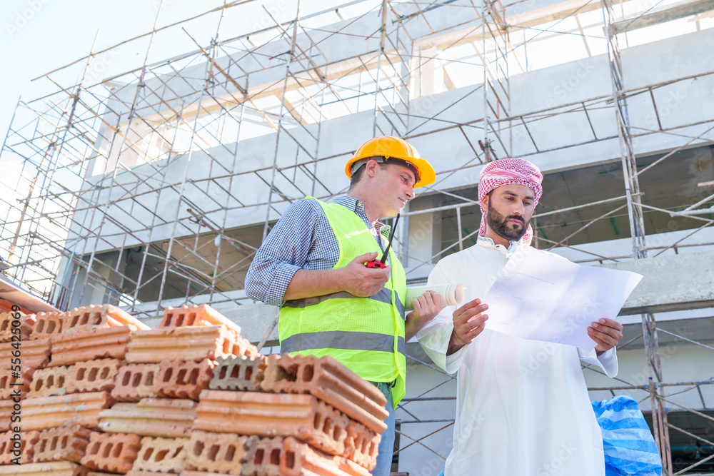 Arabic businessman teammates working together, construction engineer architect and worker looking building model and blueprint blueprint plans of Arab businessman. Arabic businessman teammates working together, construction engineer architect and worker looking building model and blueprint blueprint plans of Arab businessman.