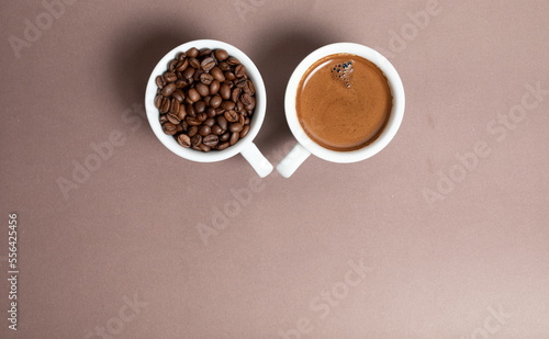 two cups of coffee on coffee beans on a brown background. © Amar