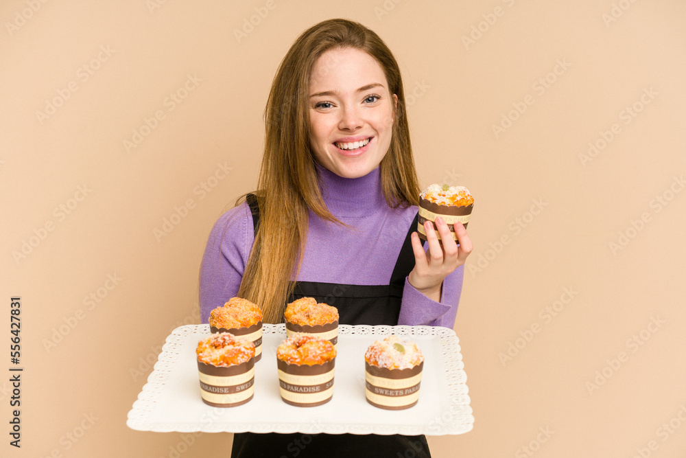 Young redhead woman holding a muffins tray cut out isolated Young redhead woman holding a muffins tray cut out isolated