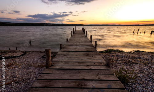 Fototapeta Naklejka Na Ścianę i Meble -  Exciting twilight at the shore with a wooden pier and moored boat