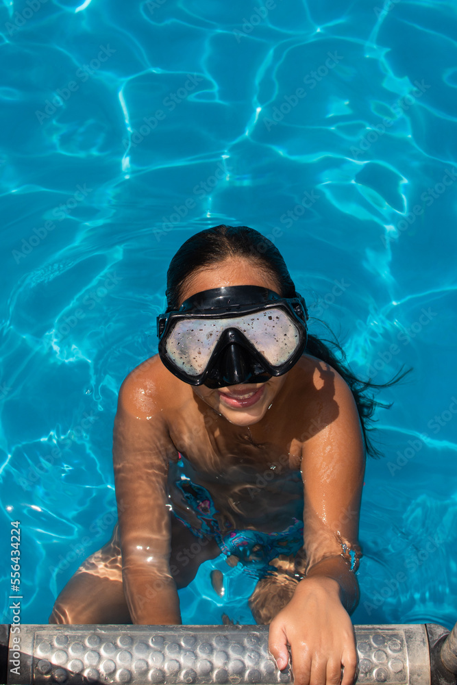 High angle shot of a girl swimming in a pool while wearing a diving mask