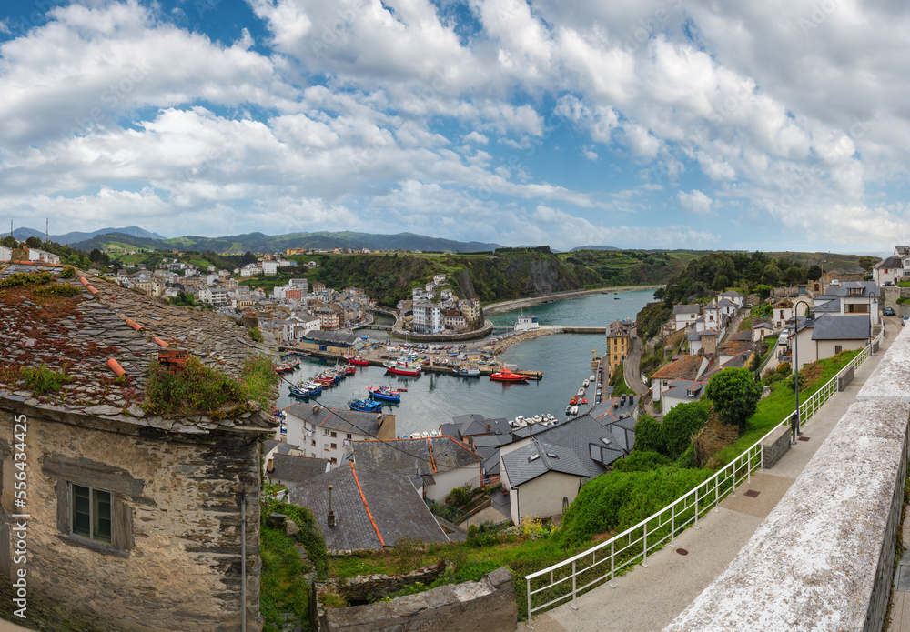Evening Luarca cityscape (top view) with colorful boats in fishing port, Asturias, Spain.