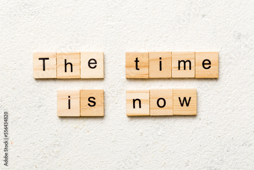 the time is now word written on wood block. the time is now text on table, concept