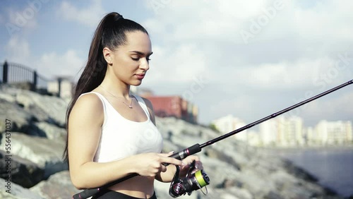 The leady fishes on the rocks in the sea. Rotate the reel. Rocks and buildings on the background. photo