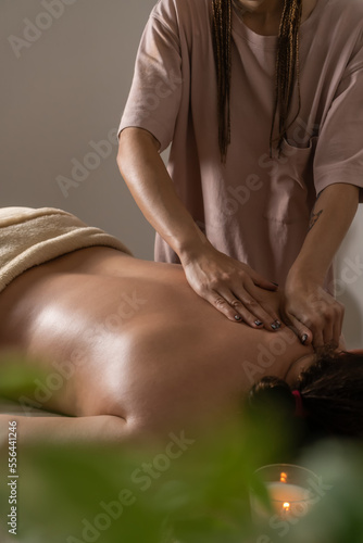 Female masseur gives a relaxing back massage to a woman in a spa salon. Concept of health, self-care. Vertical photo © Volha