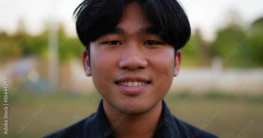 Portrait Close up of an Asian young happy farmer man looking at camera and smiling with a farmland background. Agriculture farming concept. Slow motion. Portrait Close up of an Asian young happy farmer man looking at camera and smiling with a farmland background. Agriculture farming concept. Slow motion.