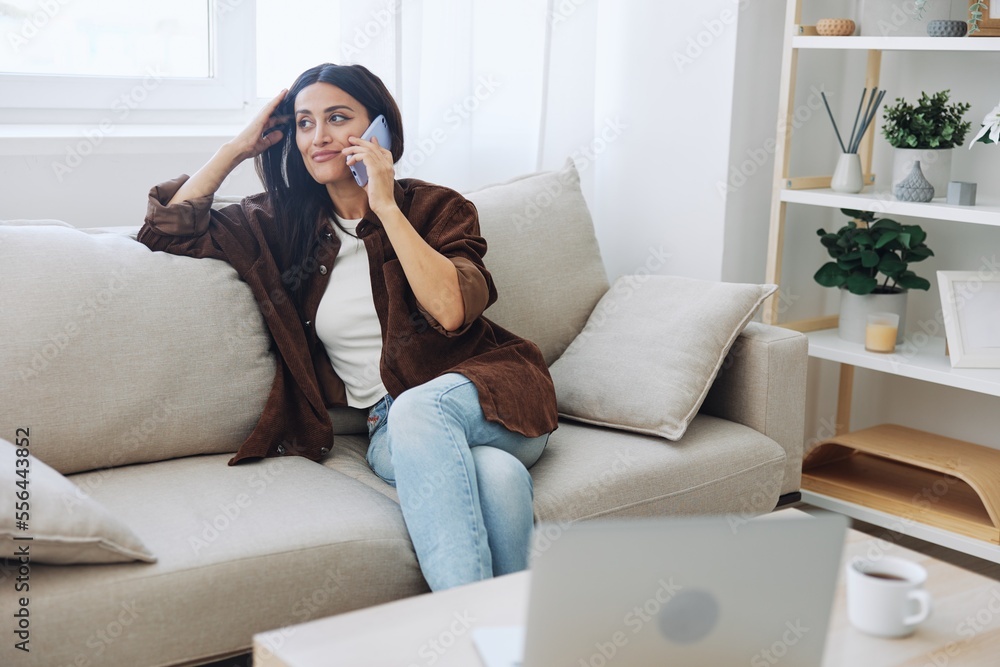 Woman blogger with phone lying at home and talking on the phone on sofa with laptop and working freelancer online, selfie Woman blogger with phone lying at home and talking on the phone on sofa with laptop and working freelancer online, selfie