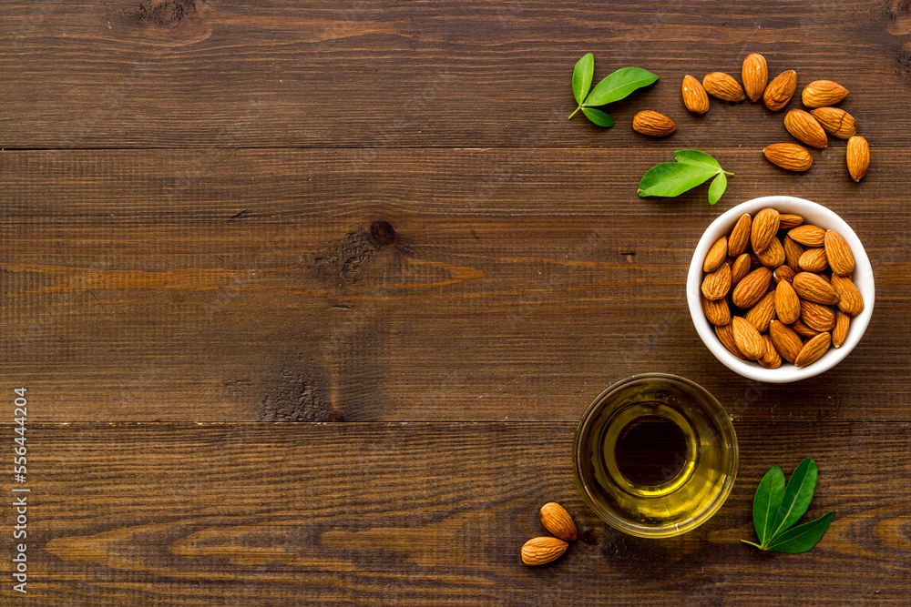 Sweet almond oil in glass jar and almond seeds with green leaf Sweet almond oil in glass jar and almond seeds with green leaf