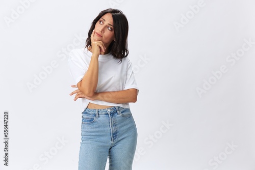 Woman in white t-shirt on white background brunette hands up gestures and signals poses in jeans emotion, lifestyle smiles, copy space